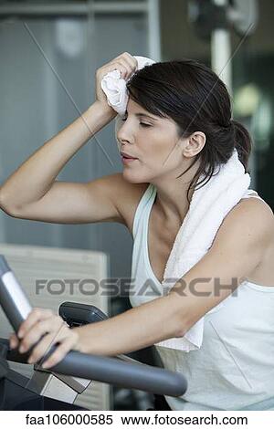 Woman working out in gym, wiping her brow with a towel View Large Photo Image Stock Photography - Woman working out in gym, wiping her brow with a towel. Fotosearch