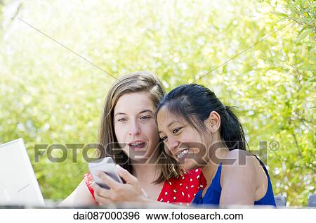 Women looking at smartphone together outdoors View Large Photo Image Stock Photograph - Women looking at smartphone together outdoors. Fotosearch
