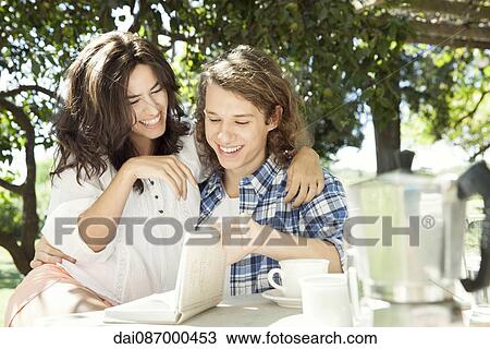 Young couple discussing book at breakfast table outdoors View Large Photo Image Stock Image - Young couple discussing book at breakfast table outdoors. Fotosearch