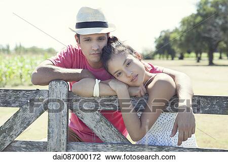 Young couple learning against wooden fence, portrait View Large Photo Image Stock Image - Young couple learning against wooden fence, portrait. Fotosearch