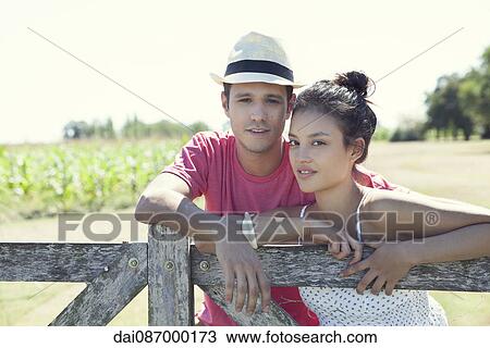 Young couple learning against wooden fence, portrait View Large Photo Image Stock Image - Young couple learning against wooden fence, portrait. Fotosearch