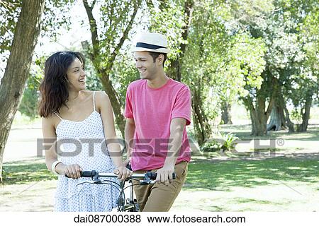 Young couple walking bicycle together View Large Photo Image Stock Photo - Young couple walking bicycle together. Fotosearch