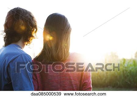 Stock Photo - Young couple watching sunset. Fotosearch