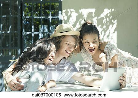 Young friends doing video chat on digital tablet View Large Photo Image Stock Photography - Young friends doing video chat on digital tablet. Fotosearch