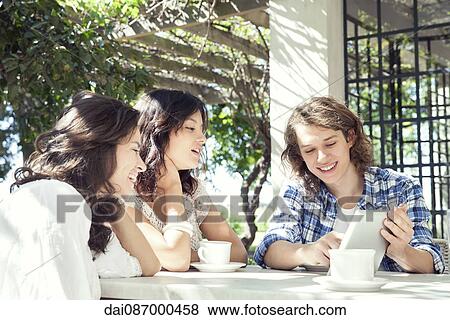 Young friends using digital tablet outdoors View Large Photo Image Stock Photo - Young friends using digital tablet outdoors. Fotosearch
