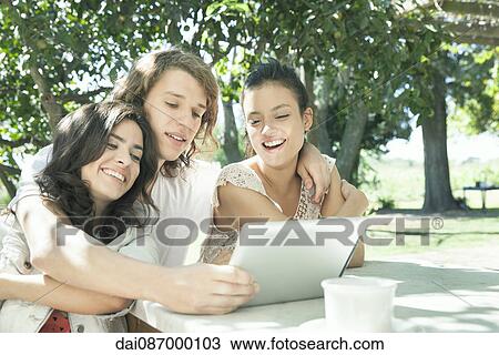Young friends watching video on digital tablet together View Large Photo Image Stock Image - Young friends watching video on digital tablet together. Fotosearch