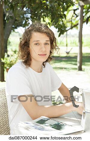 Young man at breakfast table outdoors View Large Photo Image Picture - Young man at breakfast table outdoors. Fotosearch
