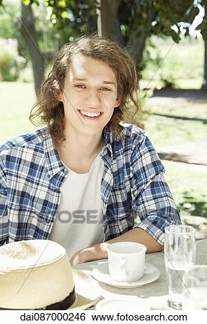 Stock Photograph - Young man enjoying coffee outdoors. Fotosearch