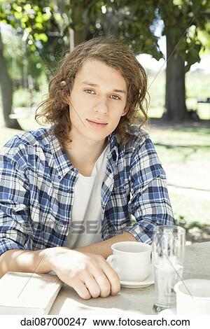 Stock Photo - Young man enjoying cup of coffee outdoors. Fotosearch