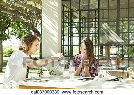 Young man pouring coffee for girlfriend at breakfast table outdoors View Large Photo Image Stock Image - Young man pouring coffee for girlfriend at breakfast table outdoors. Fotosearch