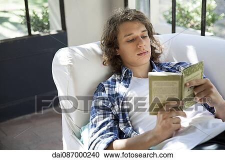 Young man reading book on couch View Large Photo Image Stock Image - Young man reading book on couch. Fotosearch