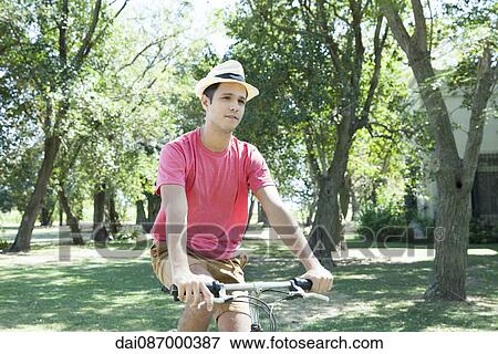 Young man riding bicycle through wooded countryside View Large Photo Image Stock Photo - Young man riding bicycle through wooded countryside. Fotosearch