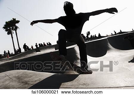 Stock Image - Young man skateboarding in skate park. Fotosearch