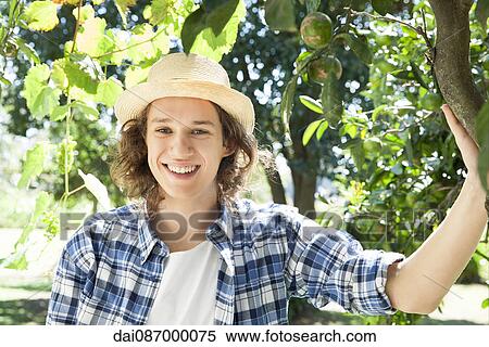 Young man standing under tree in vineyard, portrait View Large Photo Image Stock Photography - Young man standing under tree in vineyard, portrait. Fotosearch