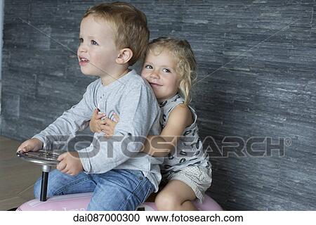 Young siblings riding together on toy car View Large Photo Image Stock Image - Young siblings riding together on toy car. Fotosearch
