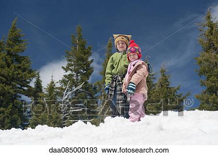 Young siblings standing together in snow View Large Photo Image Stock Image - Young siblings standing together in snow. Fotosearch