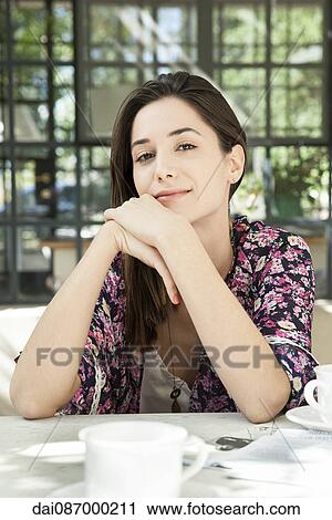 Stock Image - Young woman at breakfast table outdoors. Fotosearch