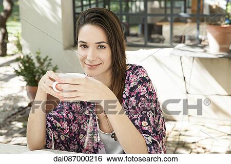 Young woman enjoying cup of coffee outdoors View Large Photo Image Stock Photograph - Young woman enjoying cup of coffee outdoors. Fotosearch