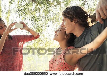 Young woman photographing her friends View Large Photo Image Stock Image - Young woman photographing her friends. Fotosearch