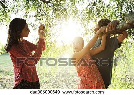 Young woman photographing her friends View Large Photo Image Stock Photo - Young woman photographing her friends. Fotosearch