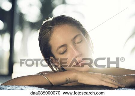 Stock Image - Young woman resting head on arms. Fotosearch