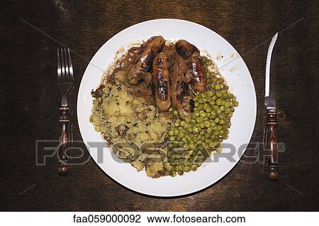 Stock Image - Bangers and mash, a dish consisting of sausage, mashed potatoes and peas. Fotosearch
