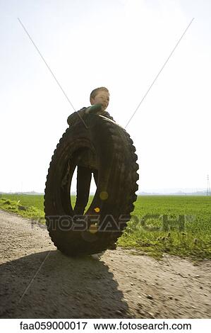 Boy rolling big tire View Large Photo Image Stock Photo - Boy rolling big tire. Fotosearch