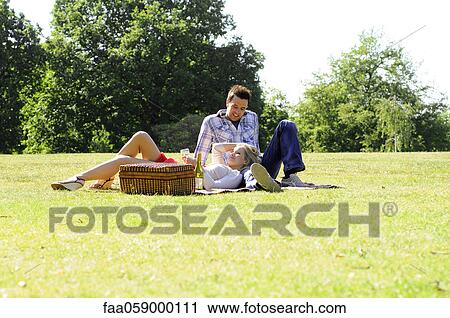 Couple enjoying picnic in park View Large Photo Image Stock Image - Couple enjoying picnic in park. Fotosearch