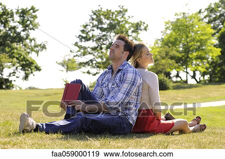 Stock Photo - Couple relaxing together in park. Fotosearch