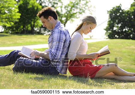 Couple sitting back to back reading in park View Large Photo Image Stock Photography - Couple sitting back to back reading in park. Fotosearch
