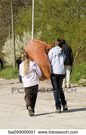 Girls carrying garbage bag together View Large Photo Image Stock Image - Girls carrying garbage bag together. Fotosearch