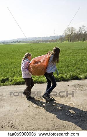 Girls carrying garbage bag together View Large Photo Image Stock Photography - Girls carrying garbage bag together. Fotosearch