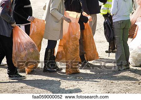 Stock Image - Group of volunteers picking up trash. Fotosearch