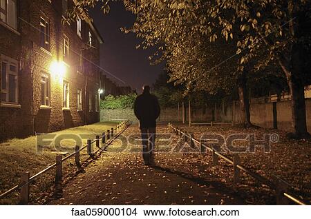 Picture - Male walking along lane at night. Fotosearch