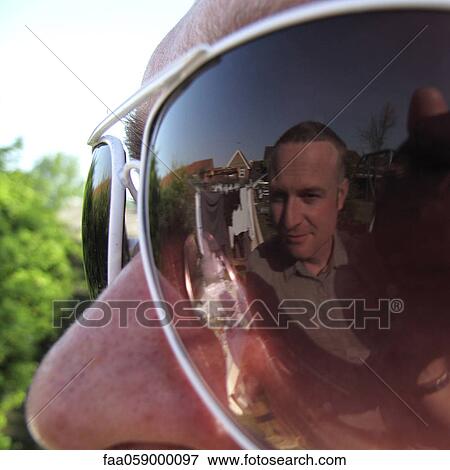 Man looking at his reflection in friend's sunglasses View Large Photo Image Stock Photo - Man looking at his reflection in friend's sunglasses. Fotosearch
