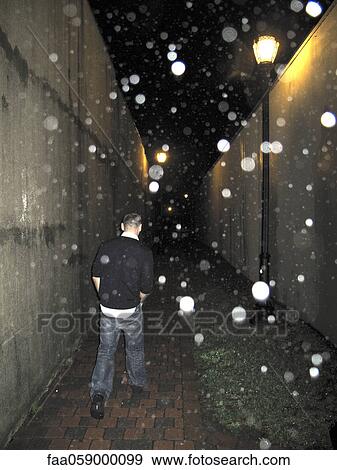 Man walking in alleyway on rainy night View Large Photo Image Stock Photo - Man walking in alleyway on rainy night. Fotosearch