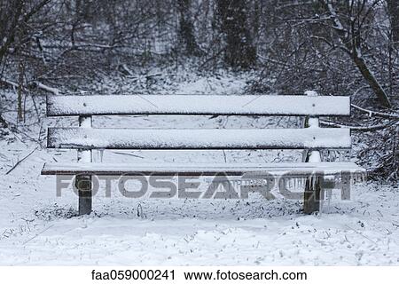 Stock Image - Park bench covered in snow. Fotosearch