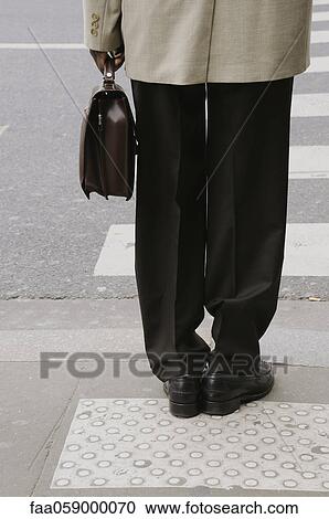 Stock Image - Pedestrian waiting at crosswalk, cropped. Fotosearch