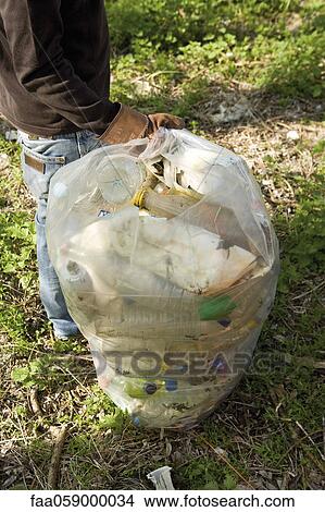 Person holding garbage bag full of plastic bottles View Large Photo Image Picture - Person holding garbage bag full of plastic bottles. Fotosearch