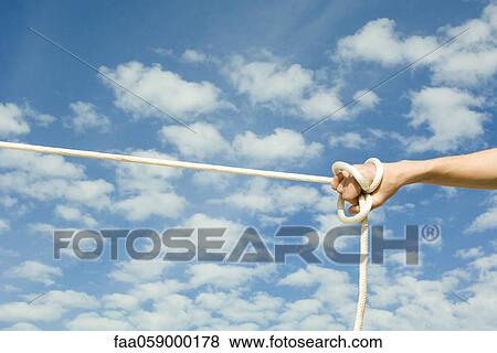 Stock Photo - Person holding on to end of rope with one hand. Fotosearch