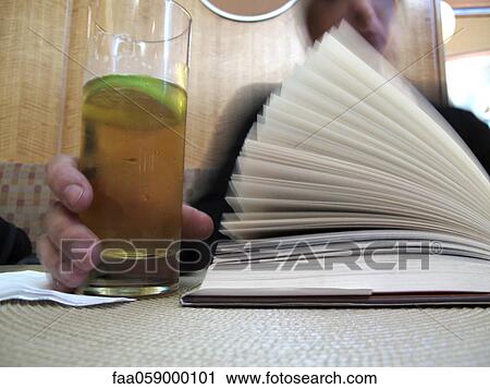 Stock Image - Person reading book in cafe, cropped. Fotosearch