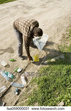 Stock Image - Picking up trash alongside dirt road. Fotosearch
