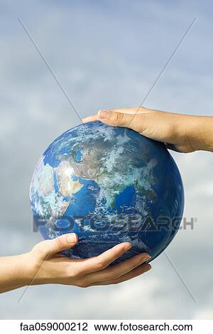 Stock Image - Two people's hands supporting one ball. Fotosearch