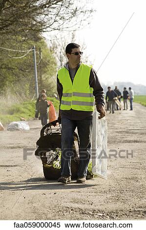 Volunteer cleaning up garbage dumped alongside road View Large Photo Image Stock Photography - Volunteer cleaning up garbage dumped alongside road. Fotosearch
