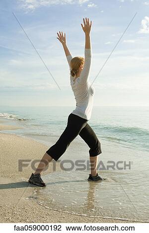 Stock Image - Woman doing yoga at the beach. Fotosearch