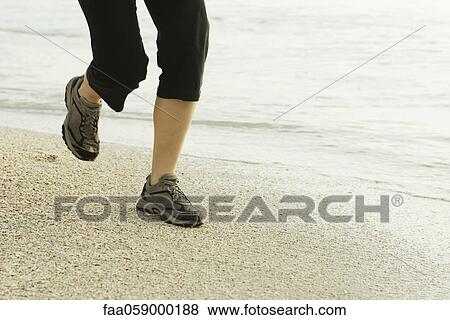 Stock Photo - Woman jogging at the beach, low section. Fotosearch