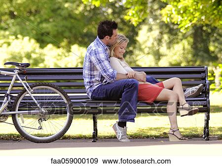 Stock Photo - Young couple relaxing together on park bench. Fotosearch