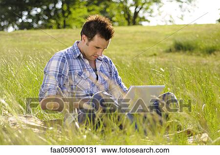 Young man using laptop computer in park View Large Photo Image Stock Image - Young man using laptop computer in park. Fotosearch