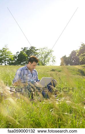 Young man using laptop computer in park View Large Photo Image Stock Image - Young man using laptop computer in park. Fotosearch