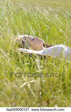 Young woman napping in tall grass View Large Photo Image Stock Photo - Young woman napping in tall grass. Fotosearch